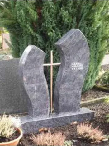 Zwei geschwungene Stelen aus geflammtem Granit mit Bronzekreuz dazwischen